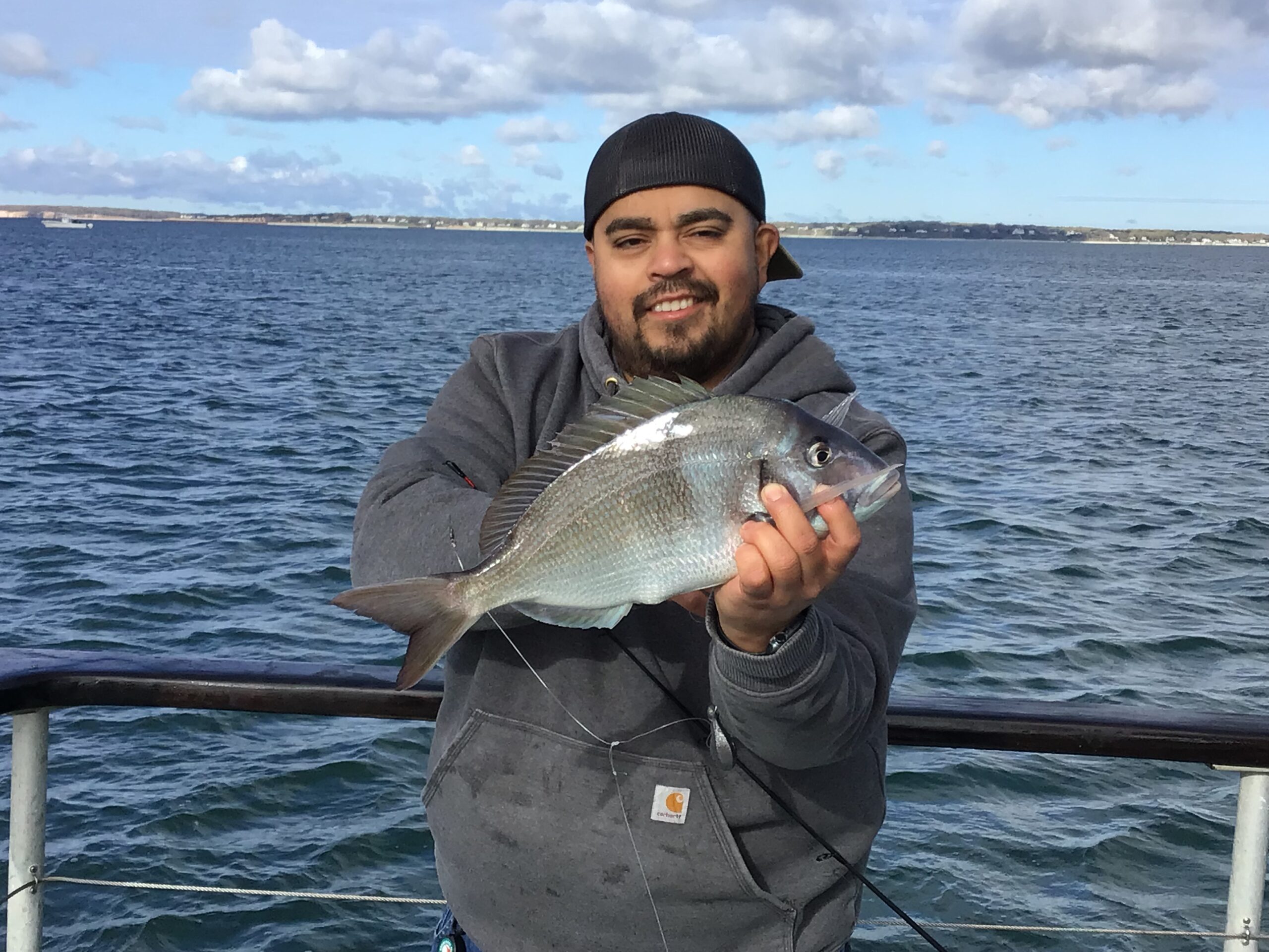 a man holding a fish in front of a body of water