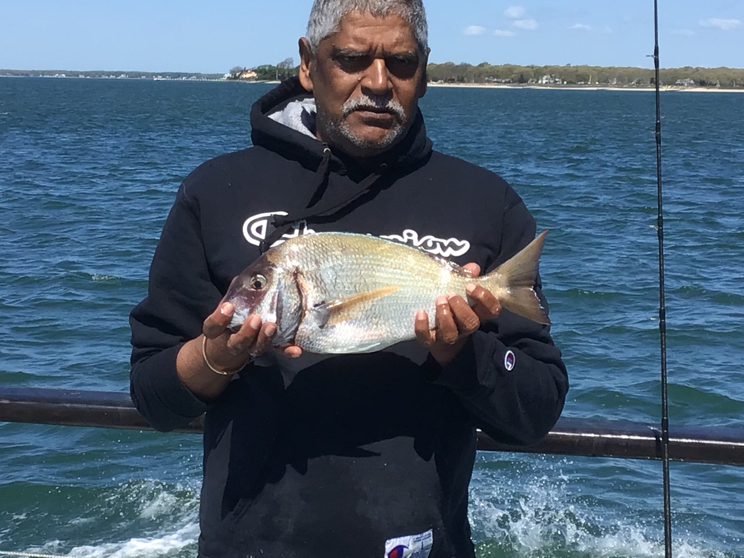 a man holding a fish on a boat in a body of water