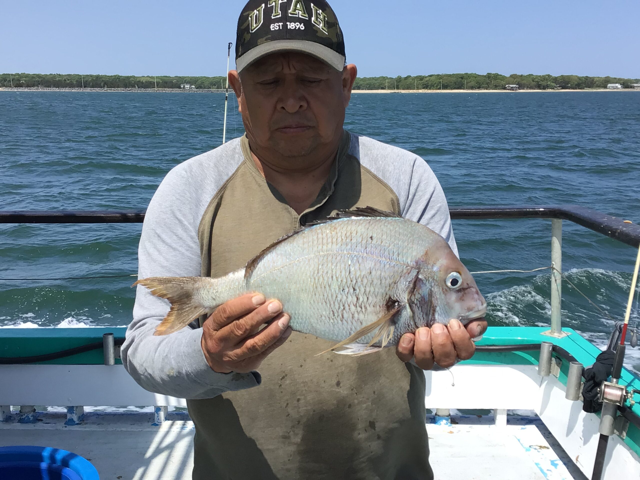Thomas Kailath holding a fish on a boat in a body of water
