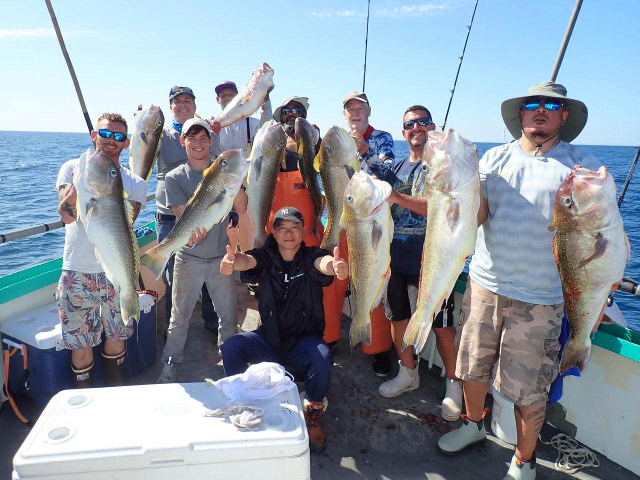 a group of people standing next to a man holding a fish