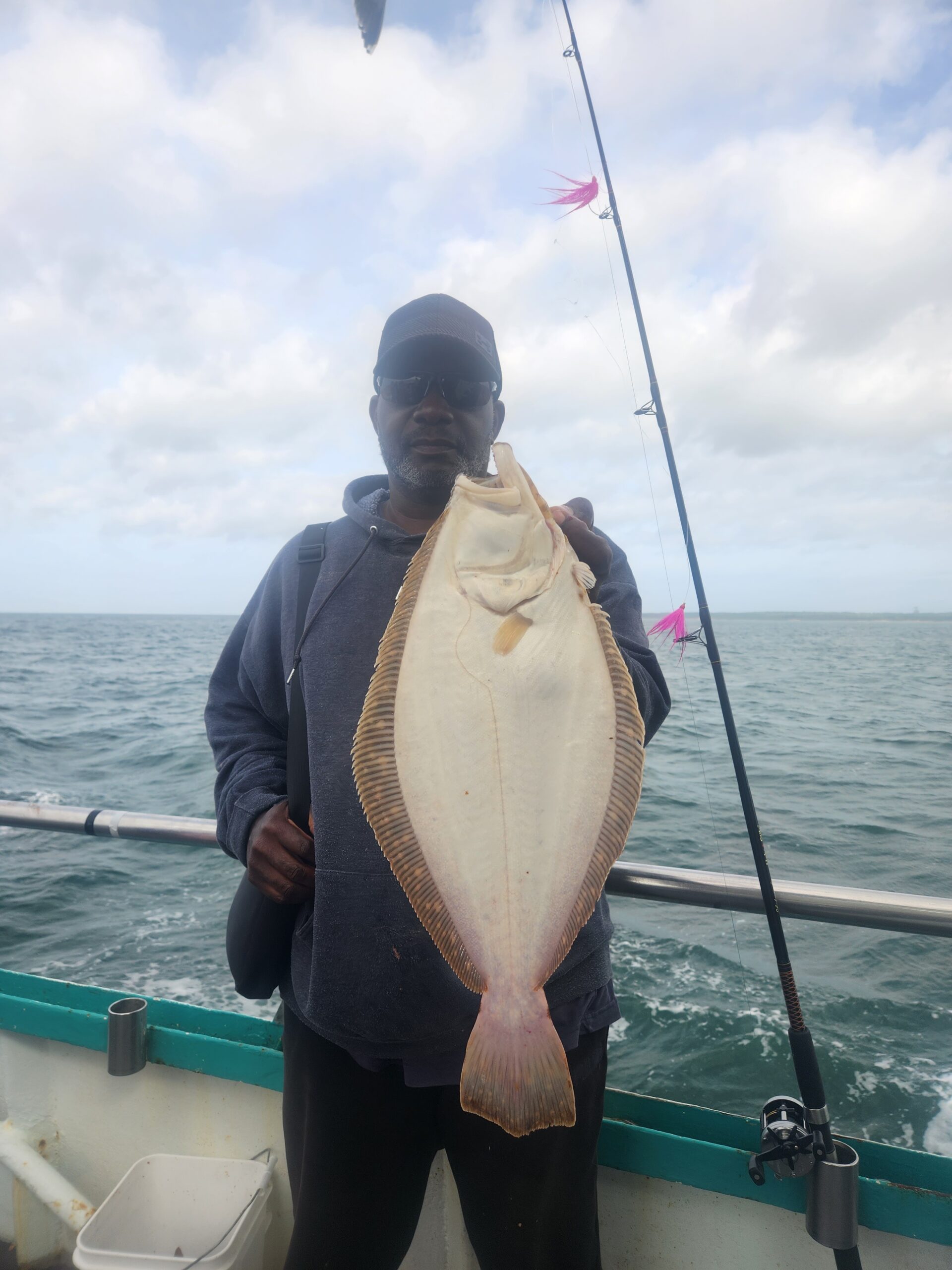 a man holding a fish on a boat in a body of water