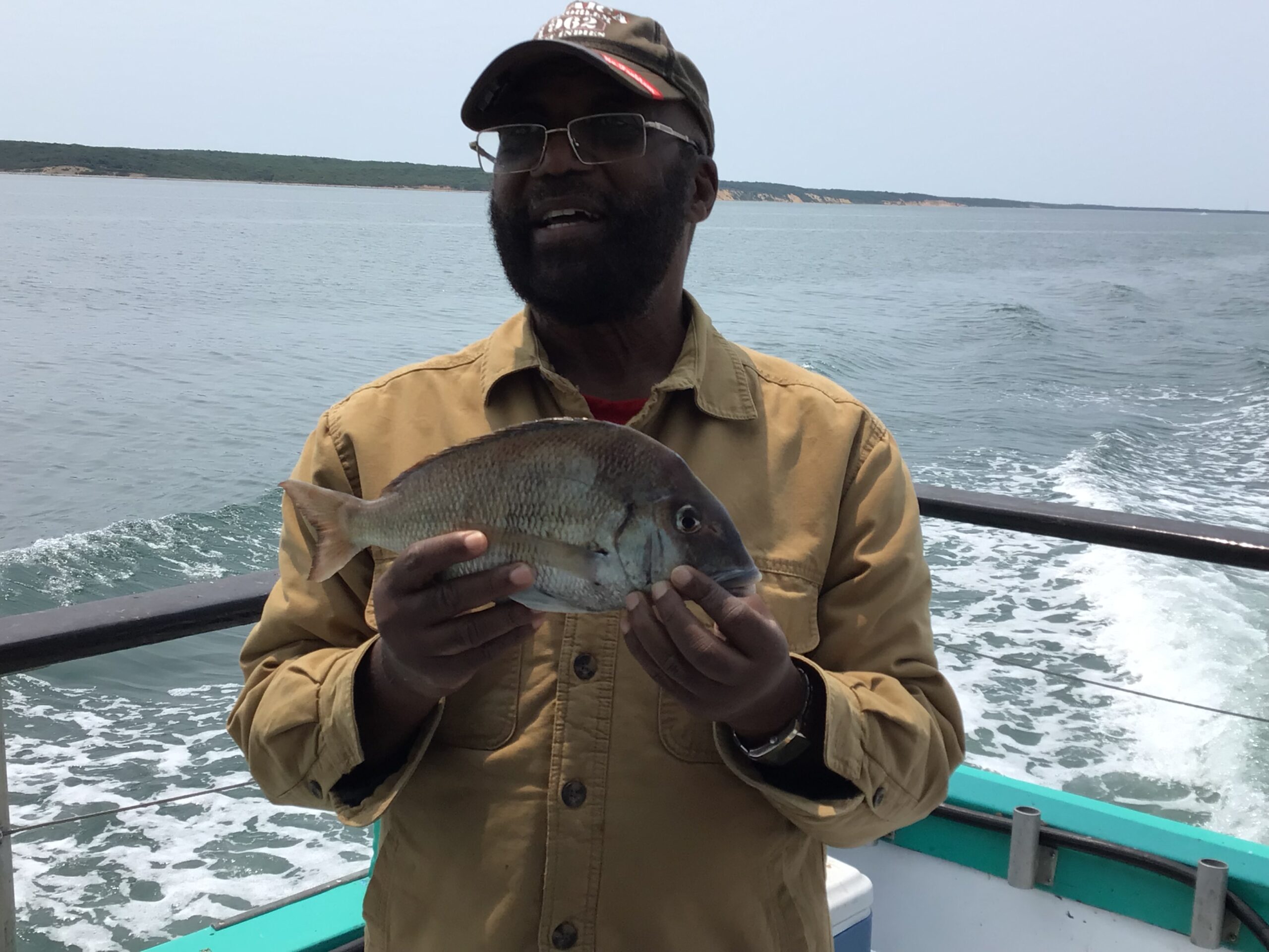 a man holding a fish on a boat in a body of water