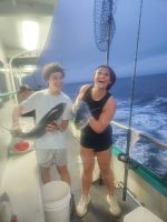 a person holding a fish on a boat posing for the camera