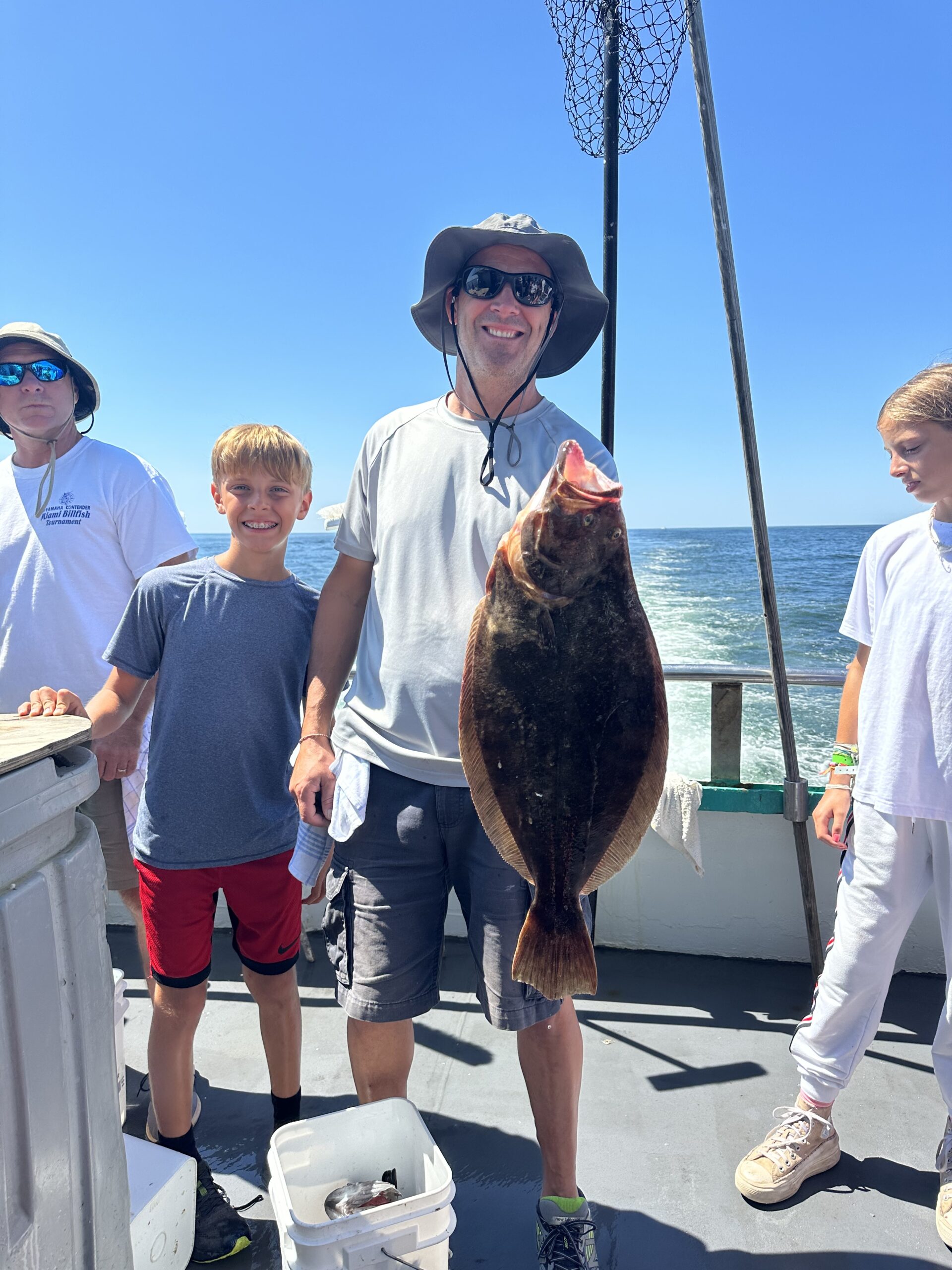 a group of people standing next to a person holding a fish