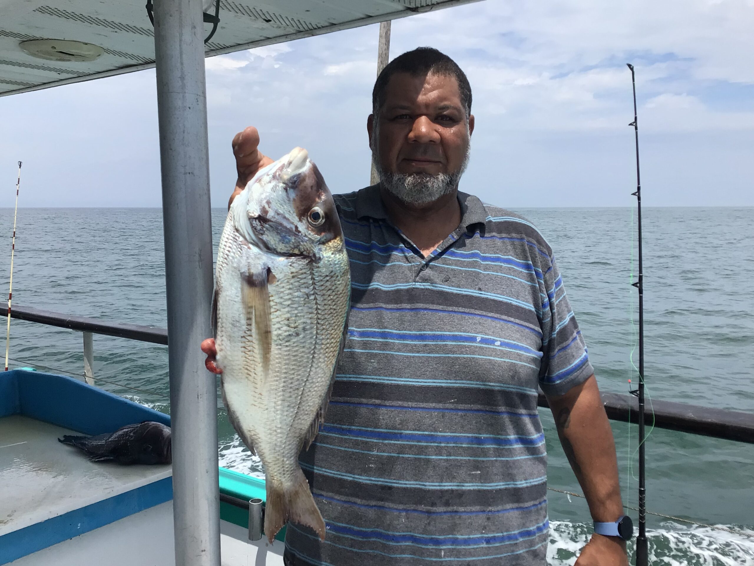a man holding a fish on a boat in a body of water