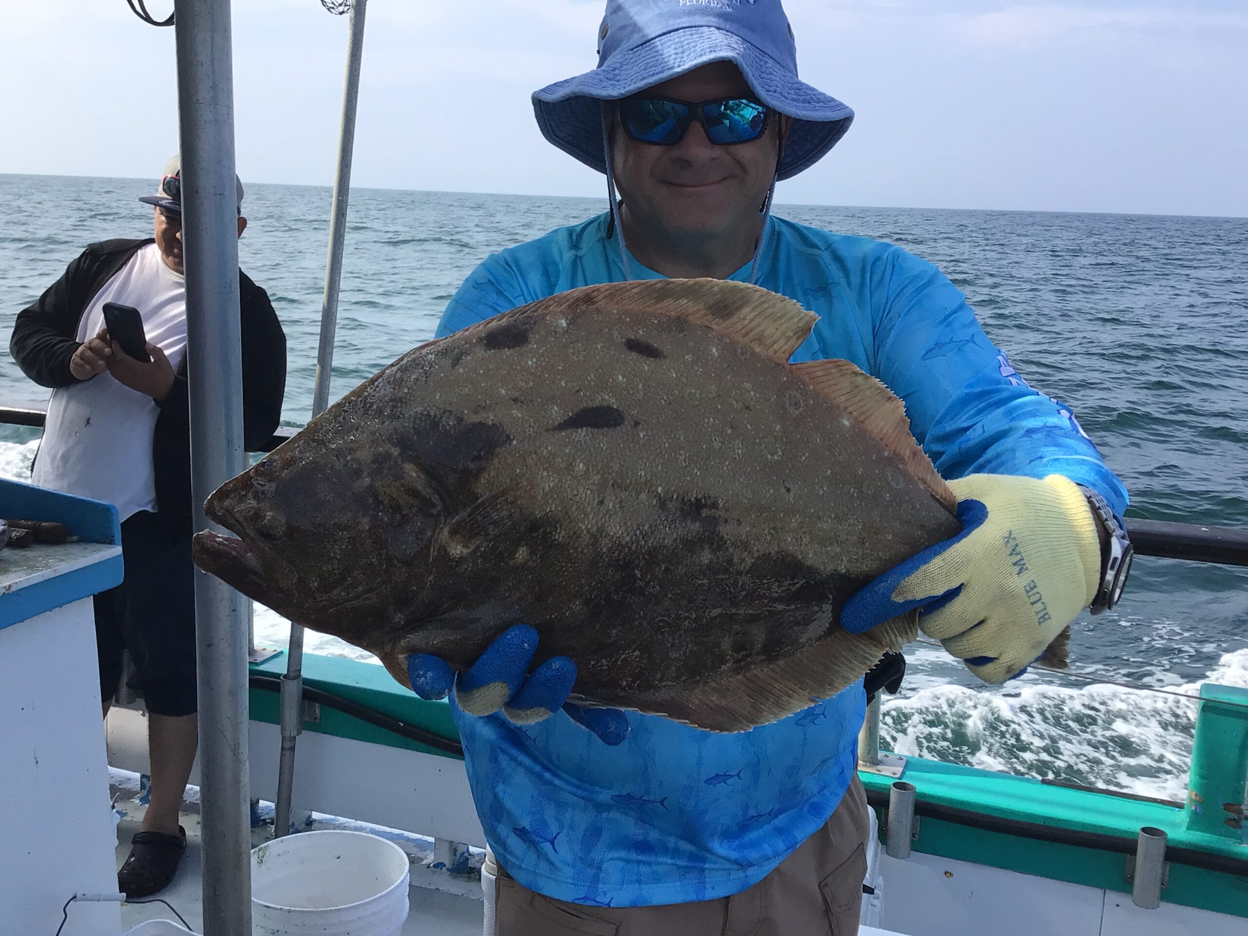 a man holding a fish on a boat in a body of water