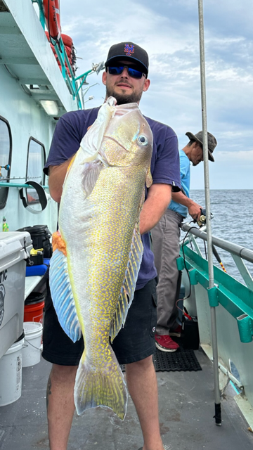 a man holding a fish on a boat