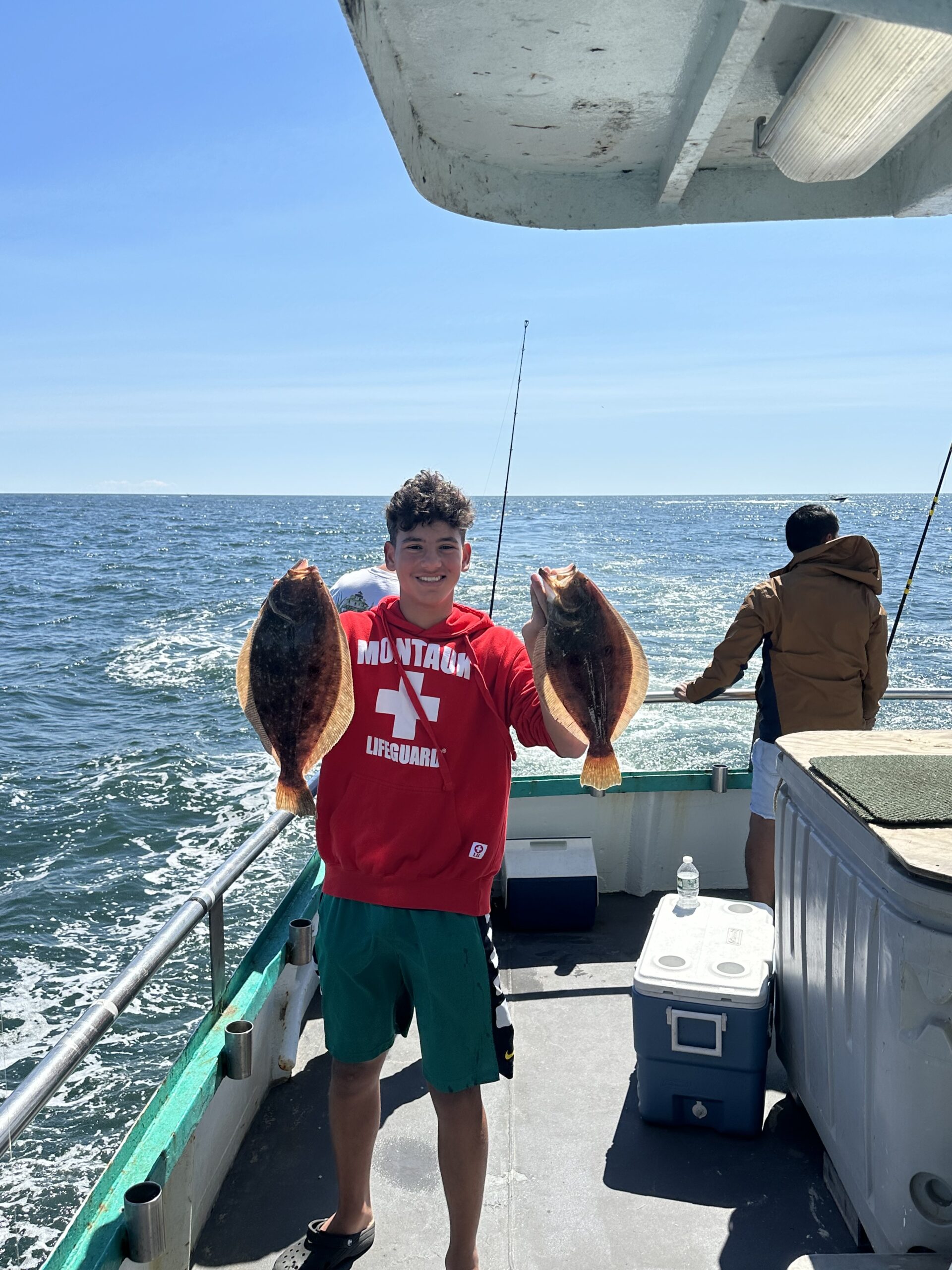 a man holding a fish on a boat in a body of water