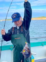 a person holding a fish on a boat in a body of water