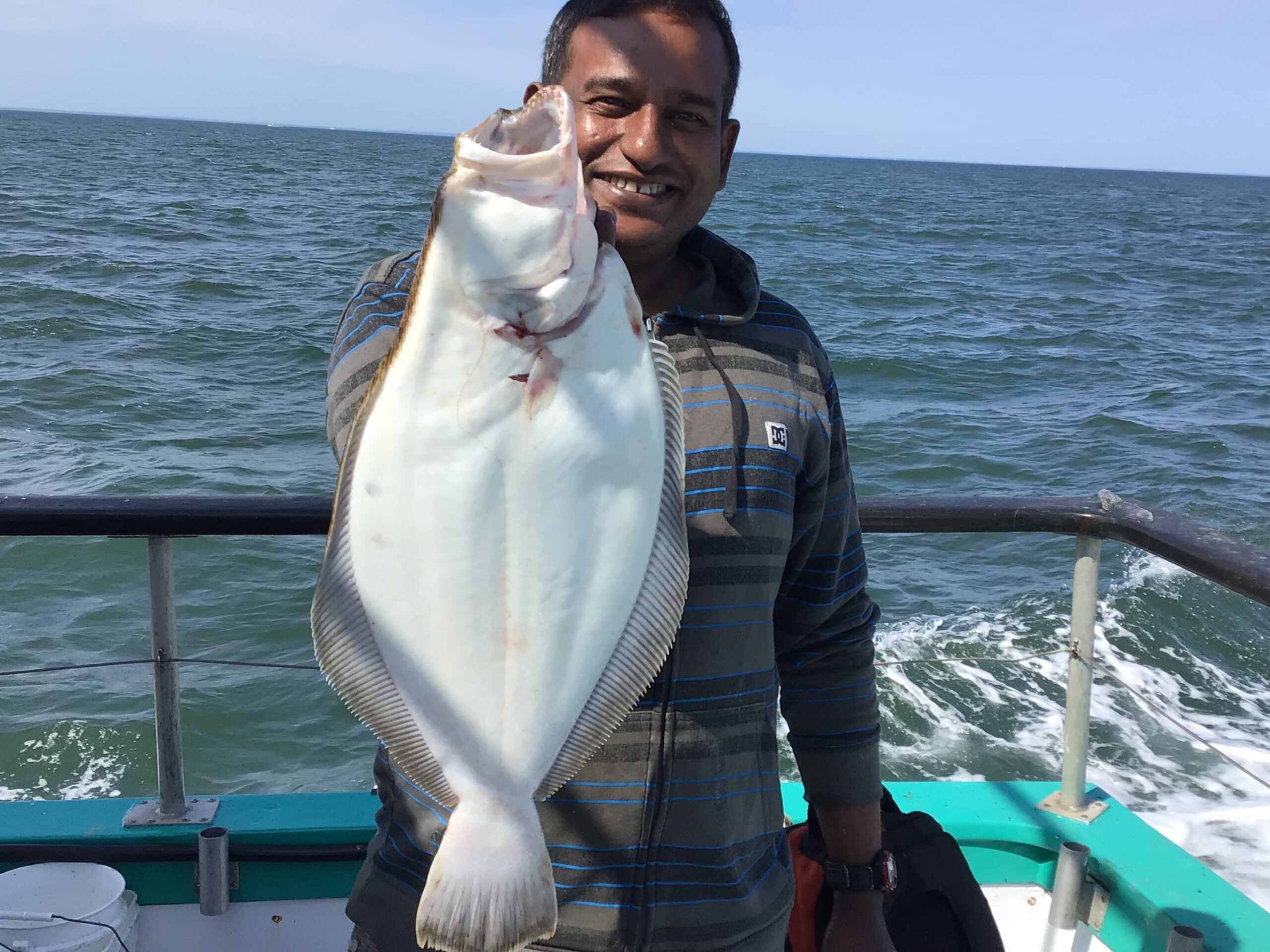 a person holding a fish in front of a body of water