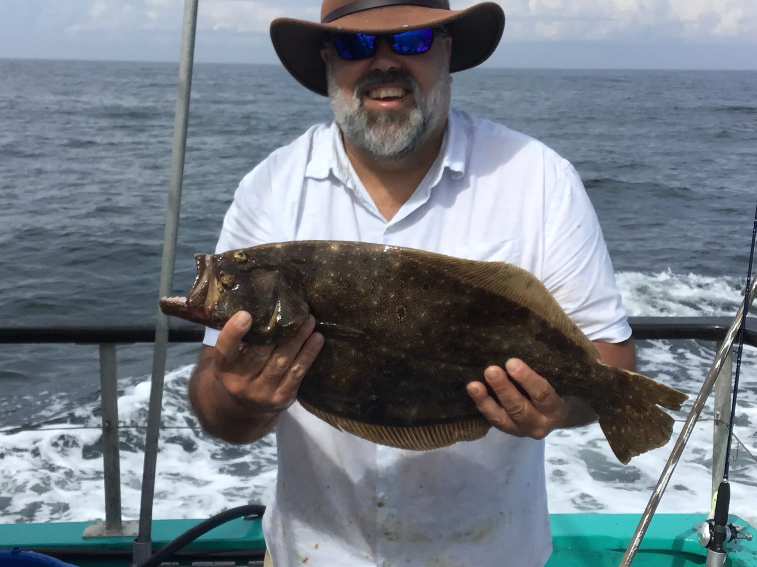 a man holding a fish on a boat in a body of water