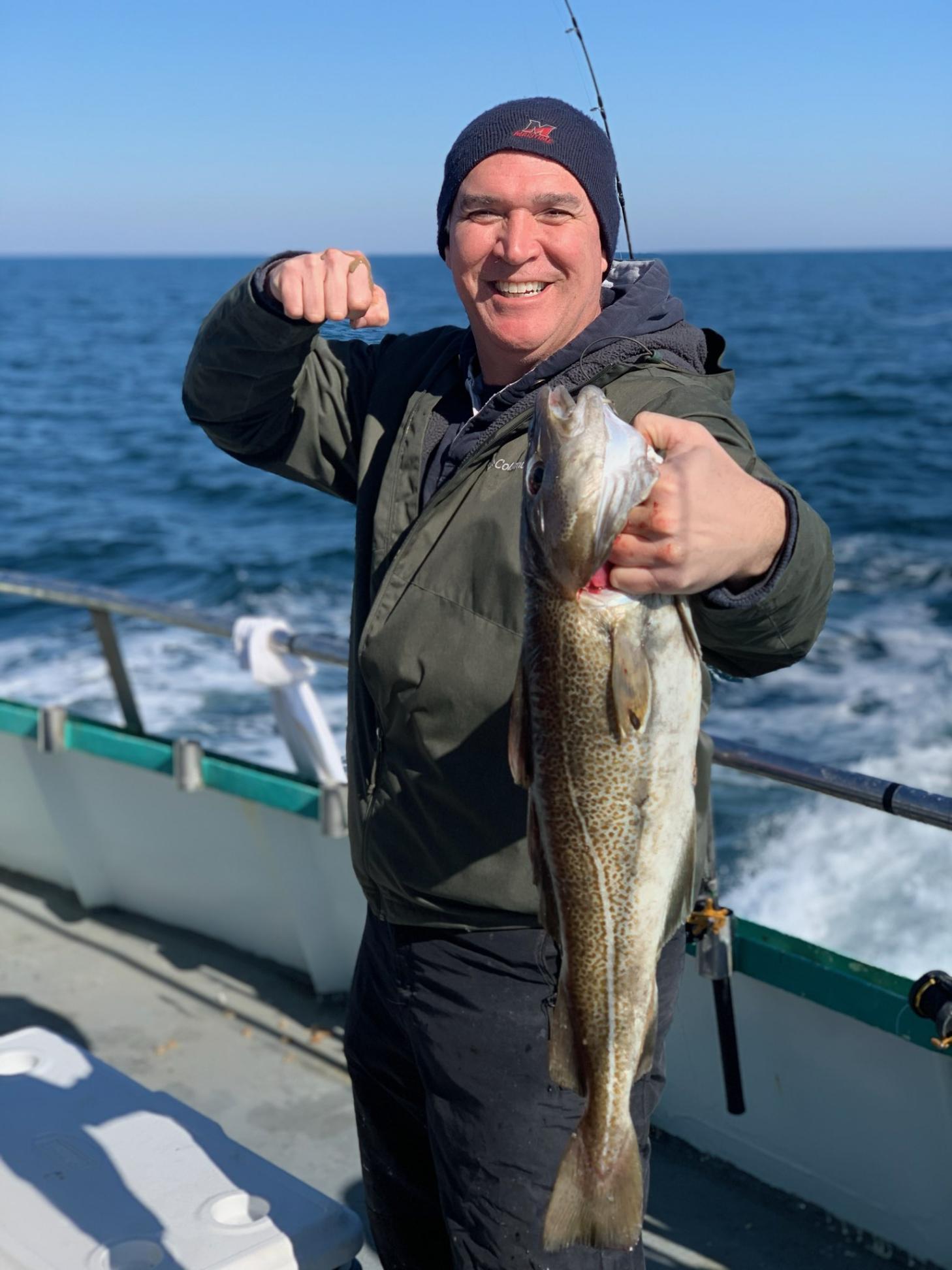 a man holding a fish on a boat in a body of water