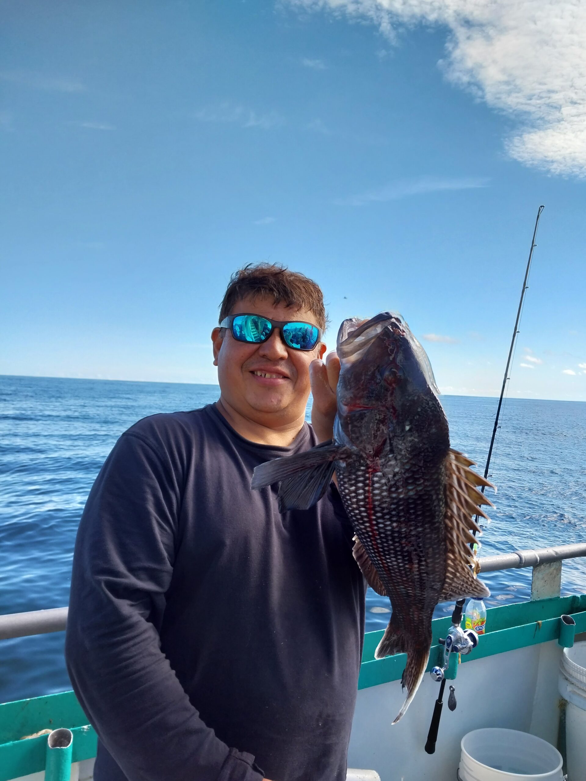 a man holding a fish on a boat in a body of water