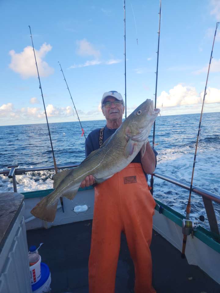 a man holding a fish on a boat in a body of water
