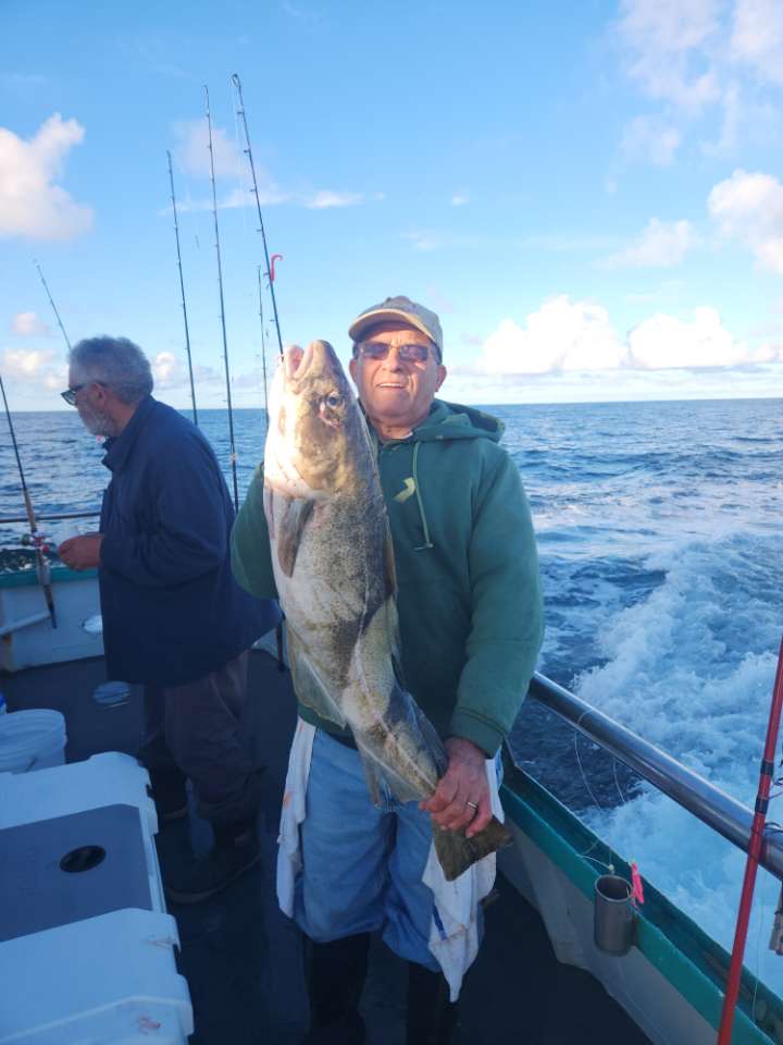 a man holding a fish on a boat posing for the camera