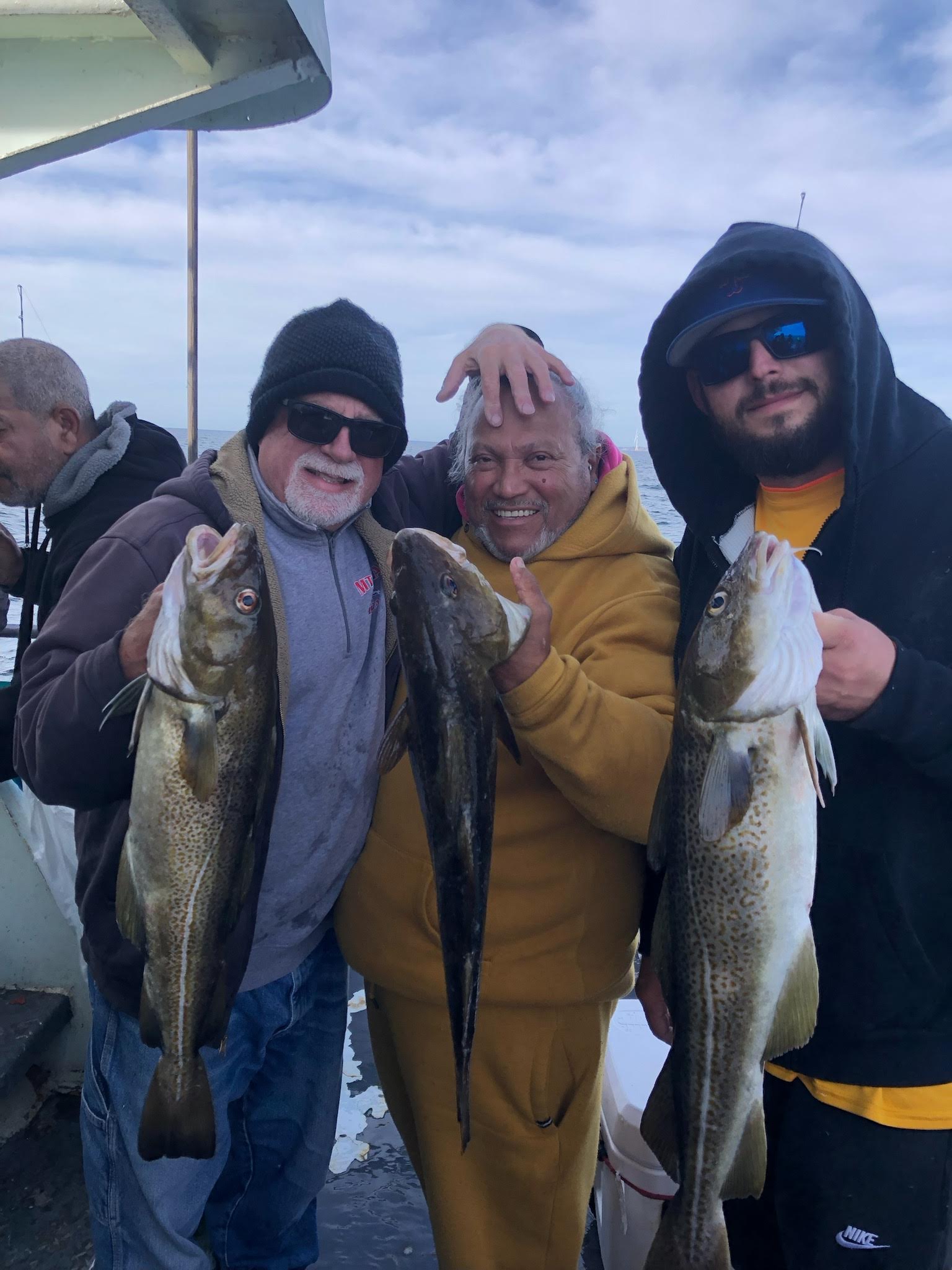 a group of people standing next to a man holding a fish
