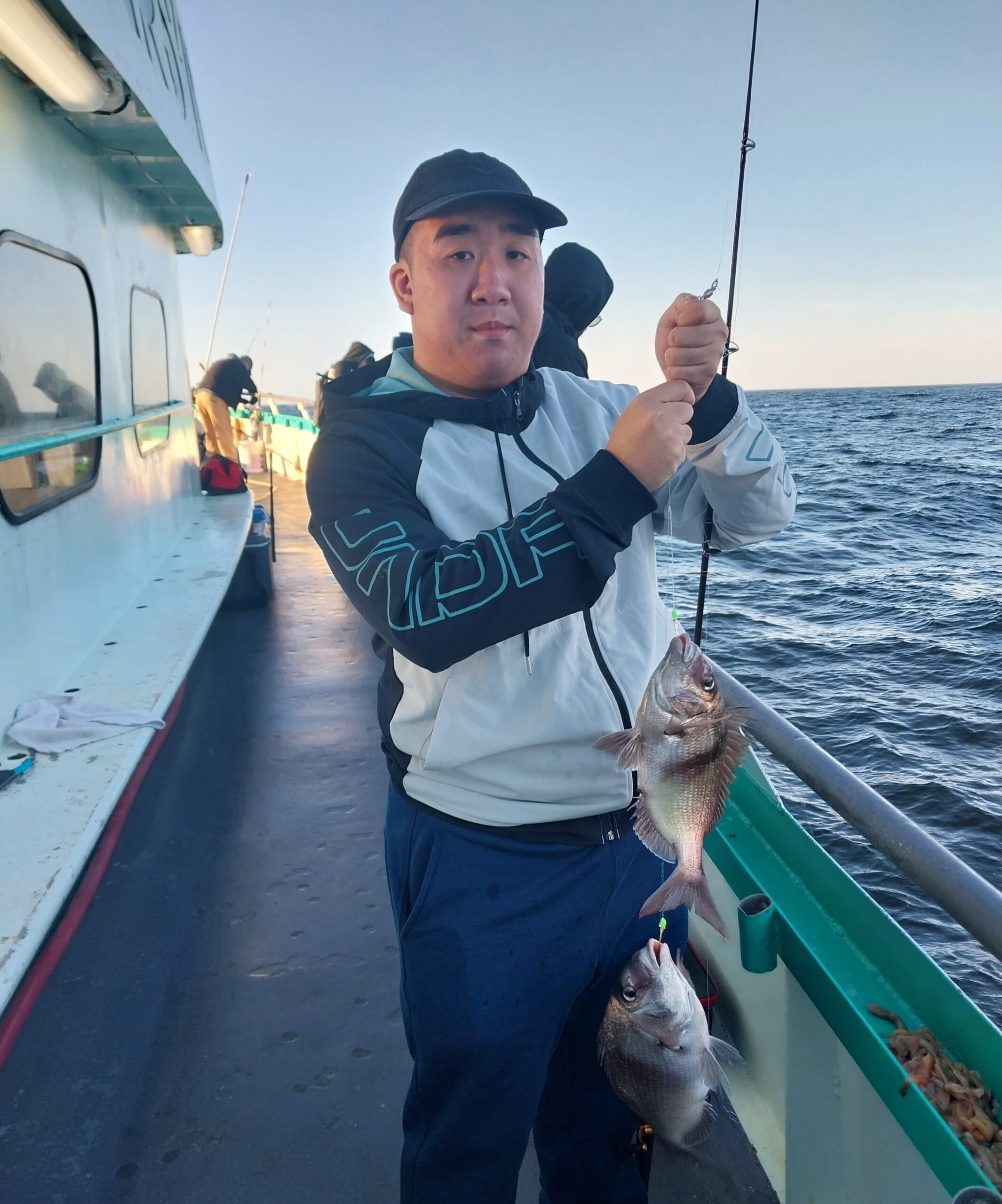 Gene Hong holding a fish on a boat