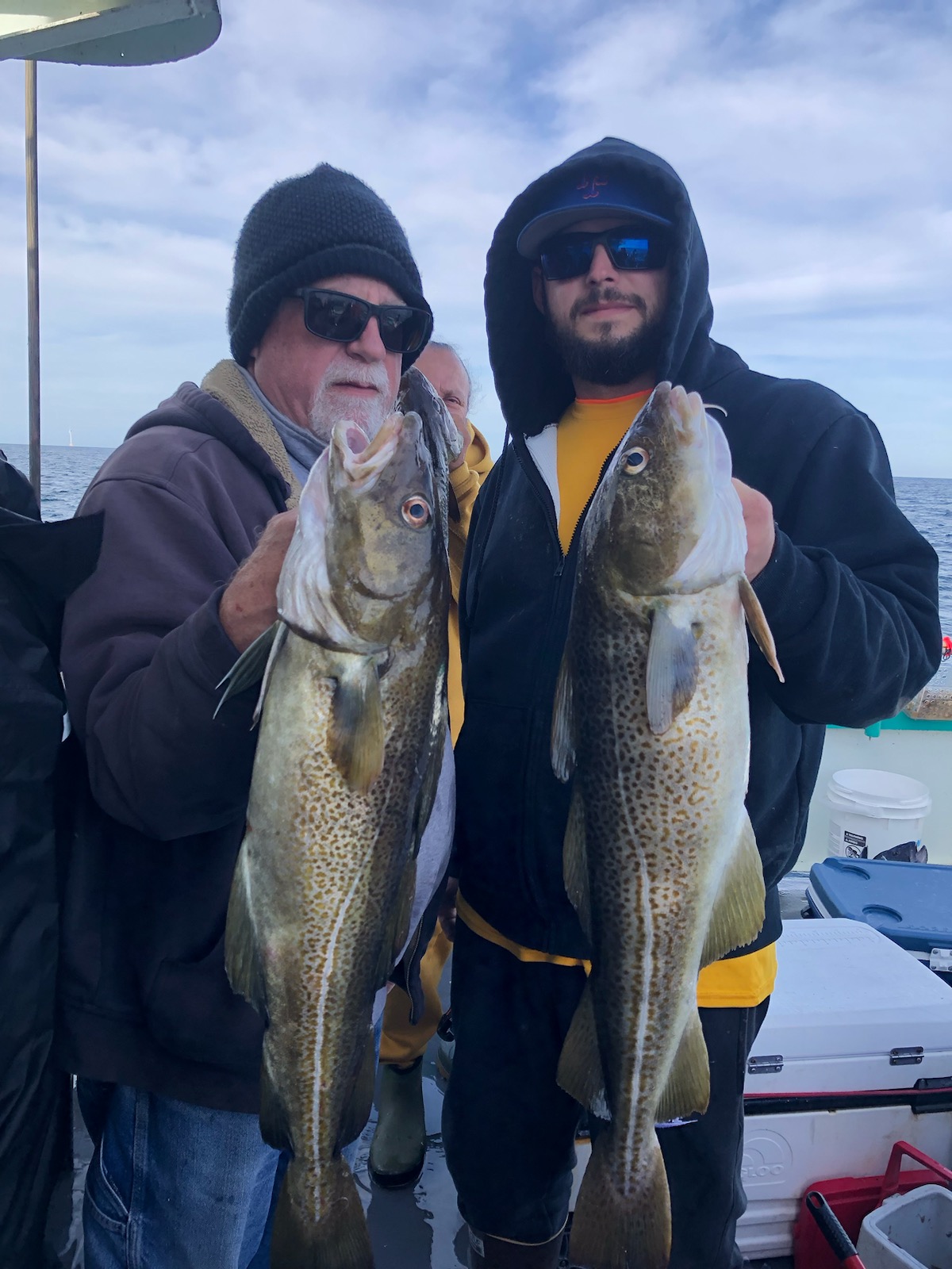 a group of people standing next to a man holding a fish