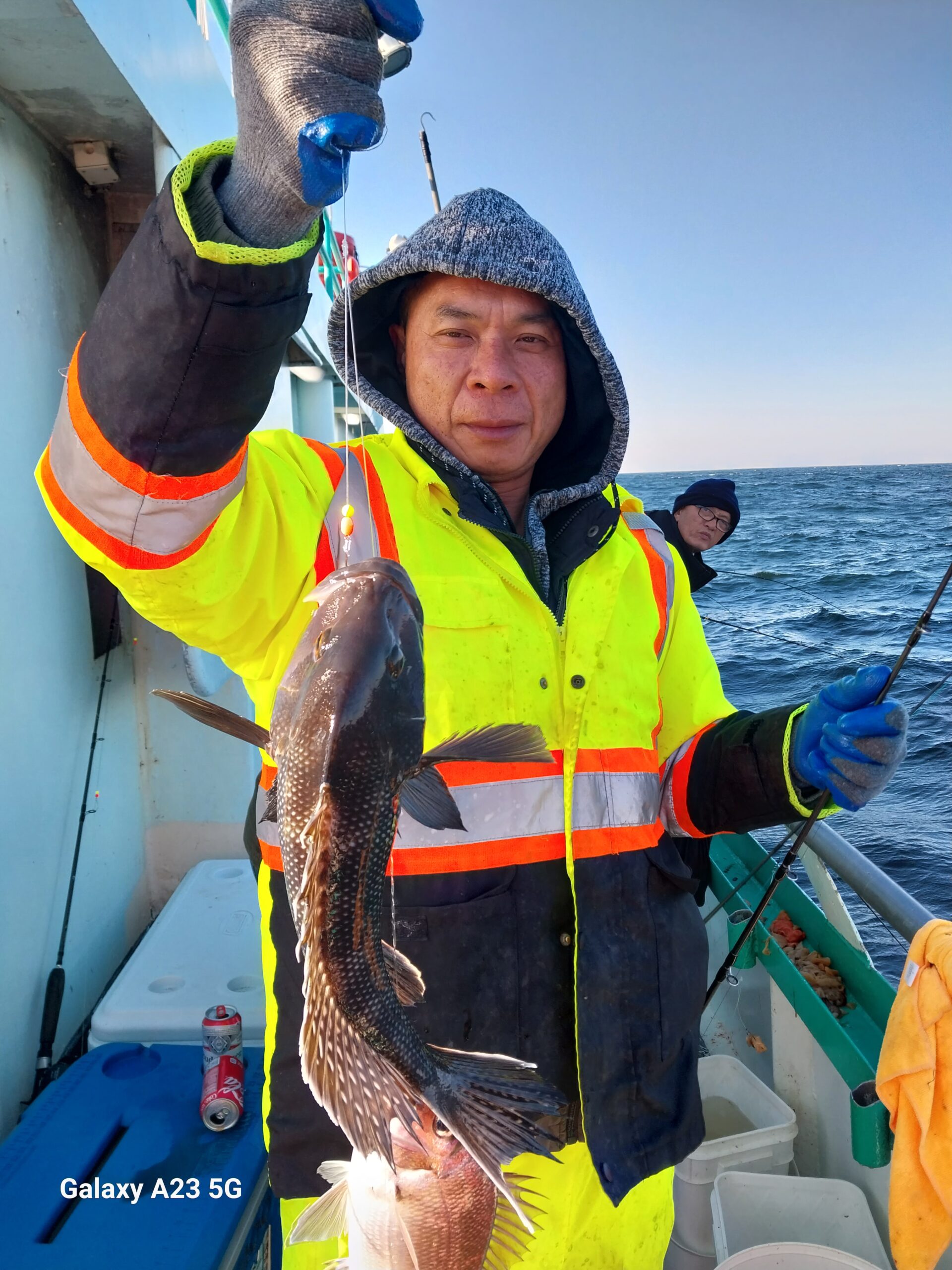 a man holding a fish on a boat posing for the camera