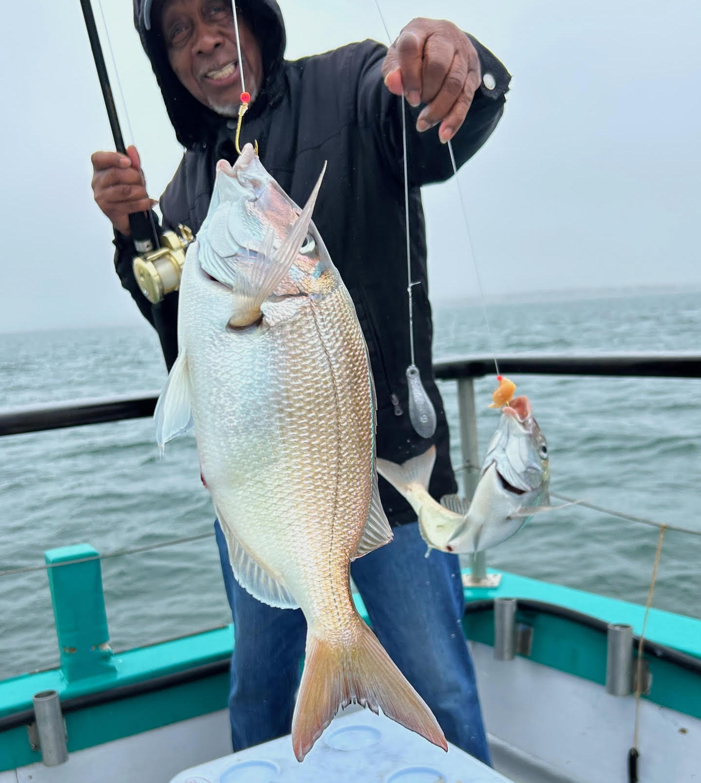 a man holding a fish on a boat in a body of water