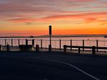 a beach with a pier in front of a sunset