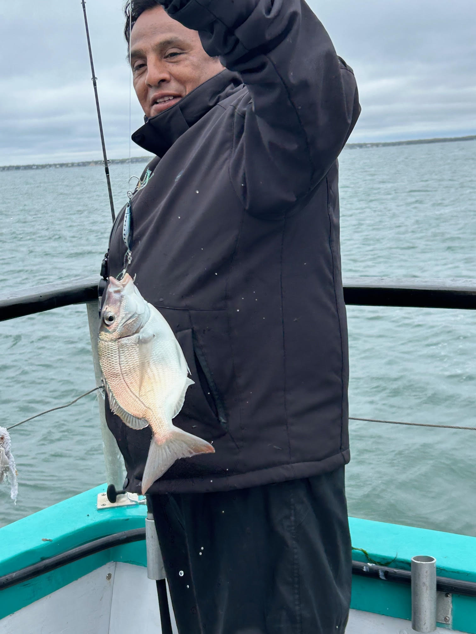 a man holding a fish on a boat in a body of water