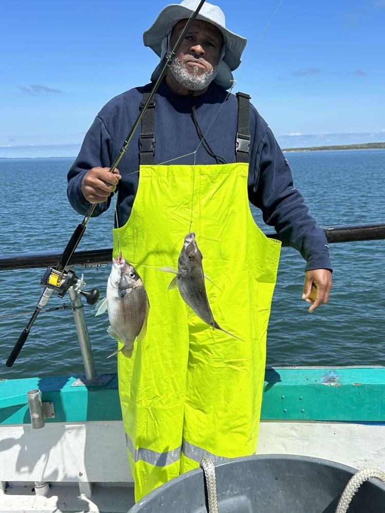 a man wearing a hat standing next to a body of water