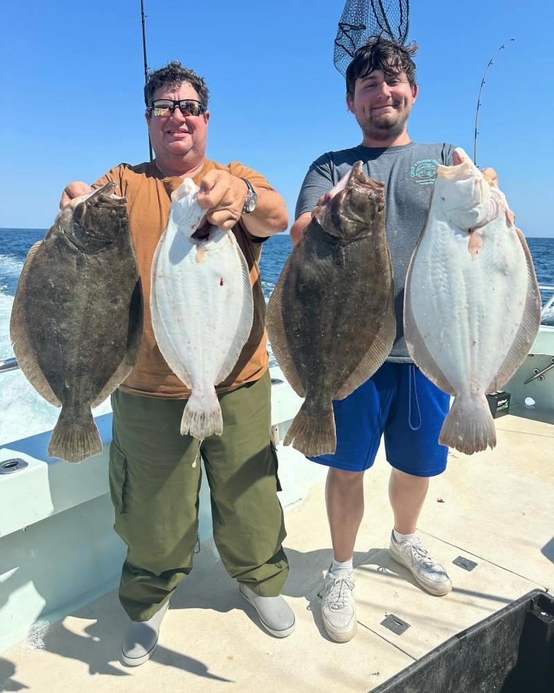 a group of people standing next to a man holding a fish