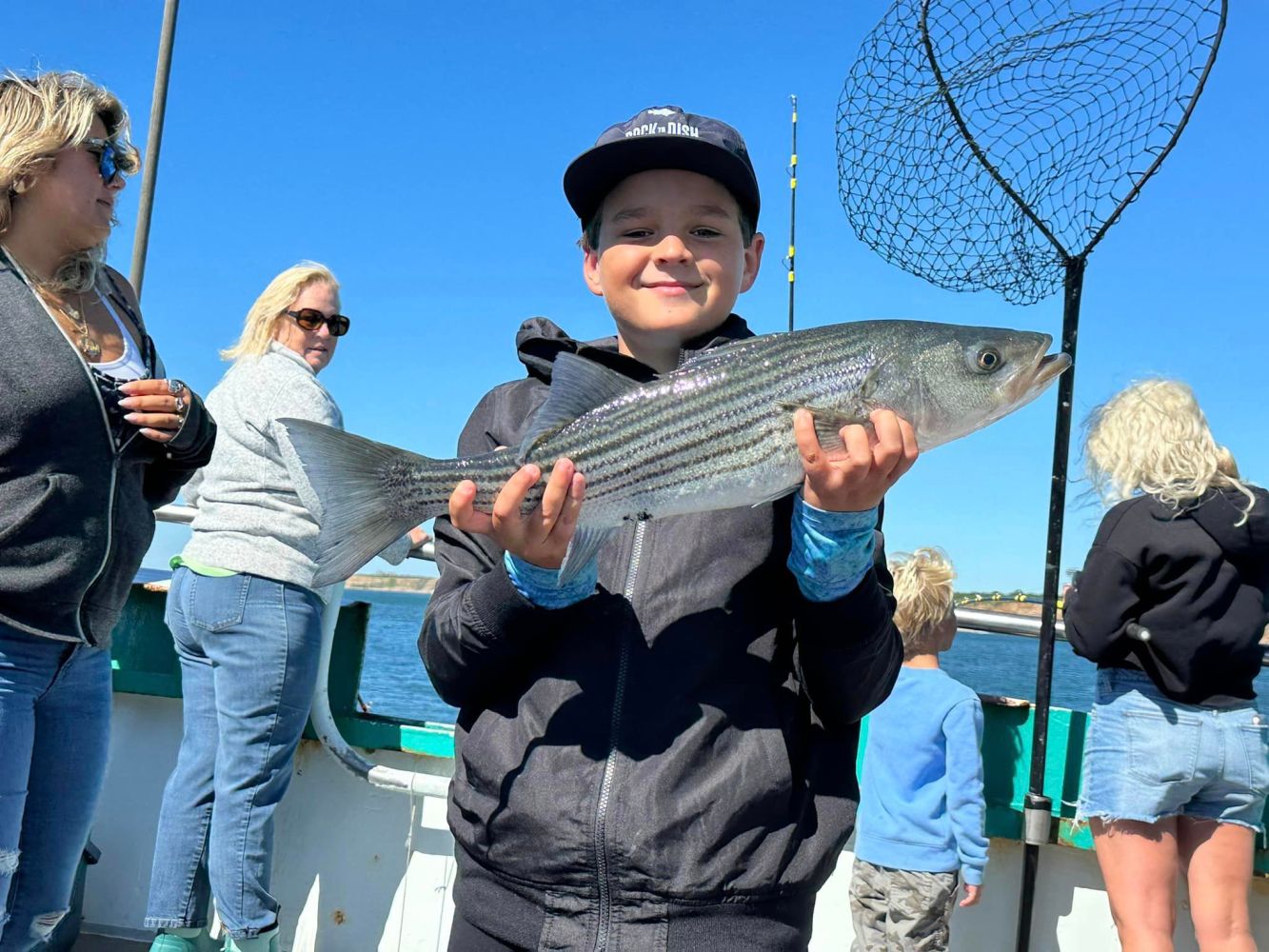 a group of people standing next to a person holding a fish