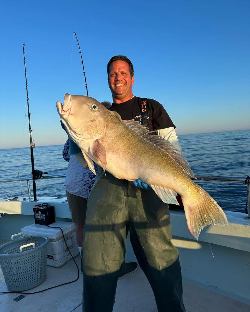 a man holding a fish on a boat in a body of water