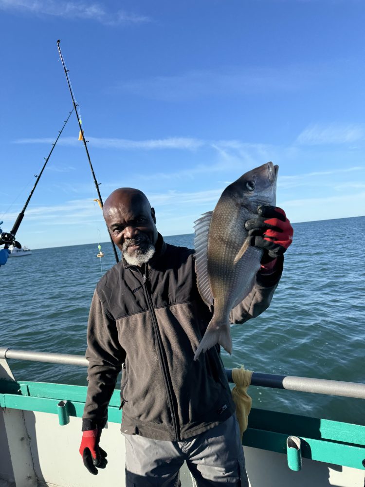 a man holding a fish on a boat in a body of water