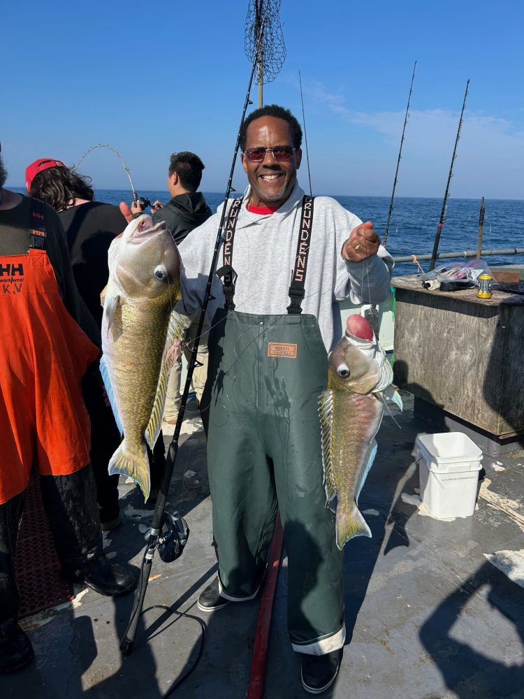 a group of people standing next to a person holding a fish