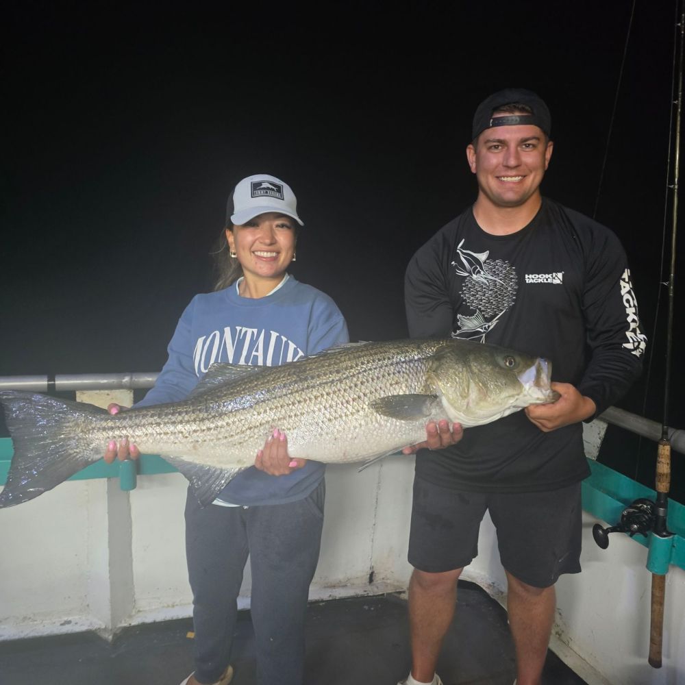 a person holding a fish posing for the camera