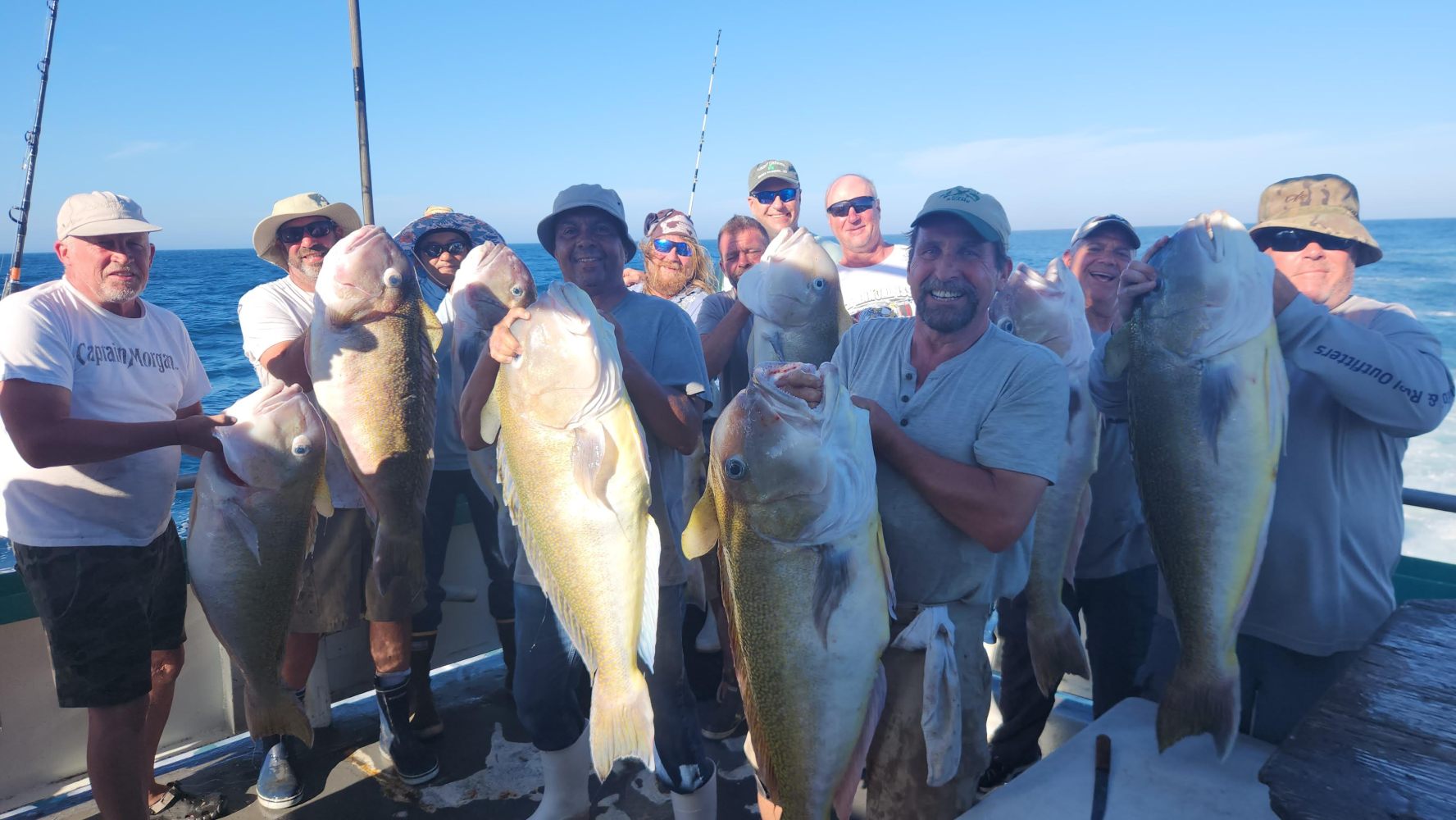 a group of people standing next to a man holding a fish