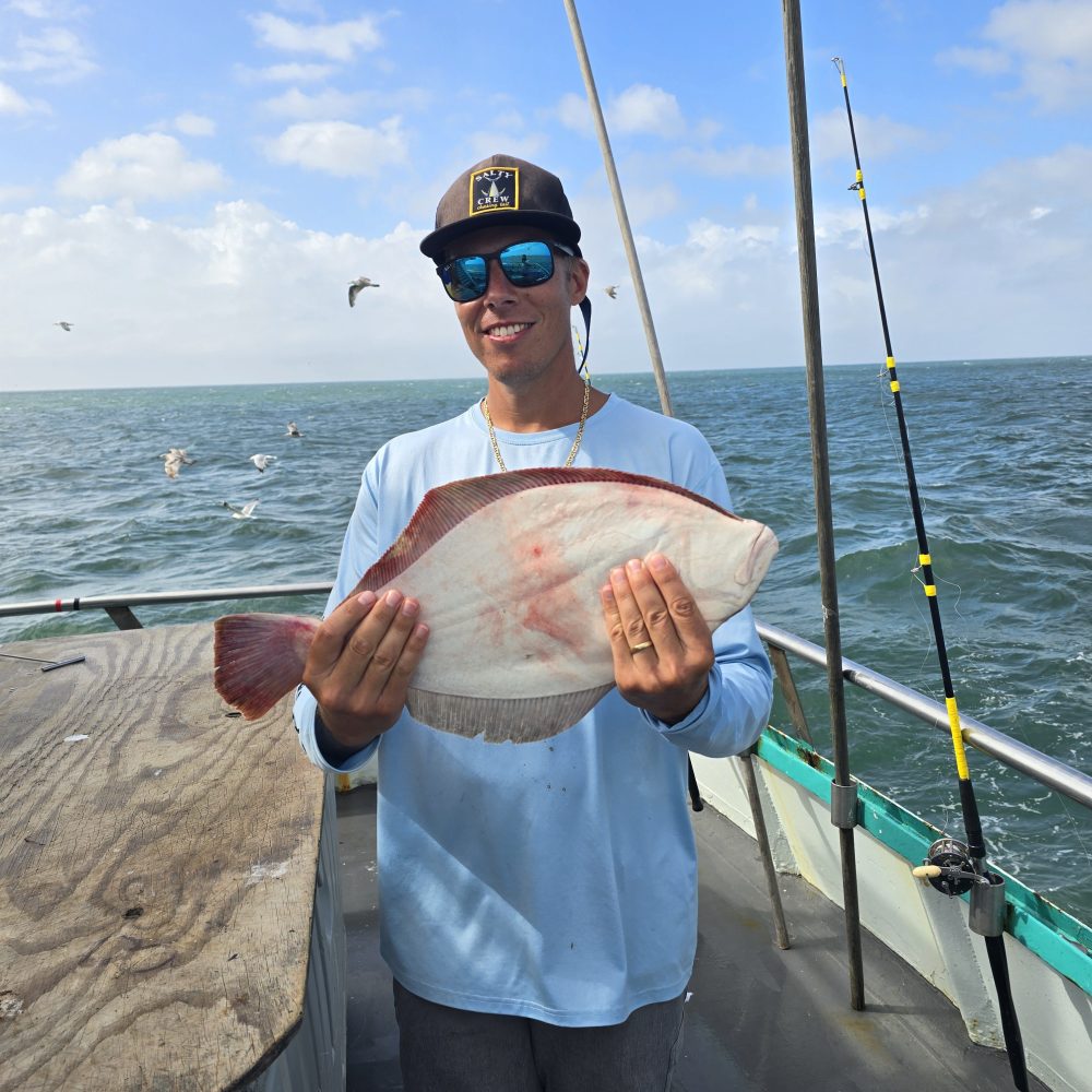 a man holding a fish on a boat in a body of water