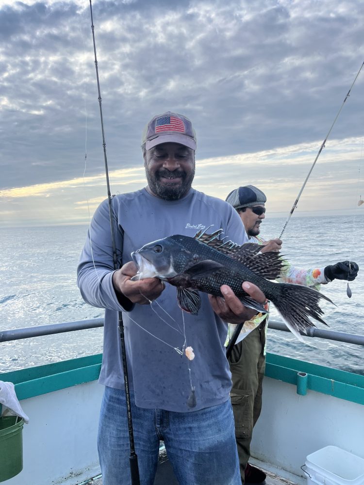 a man holding a fish on a boat in a body of water