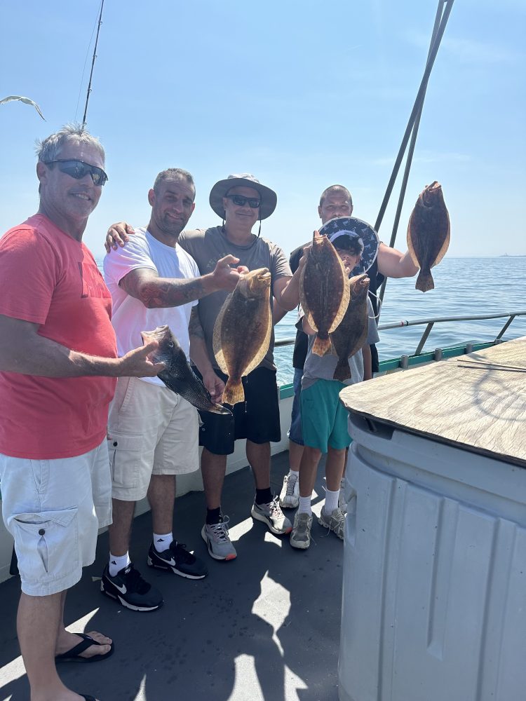 a group of people standing next to a man holding a fish