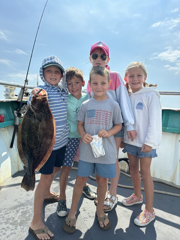 a group of people standing next to a little boy holding a fish