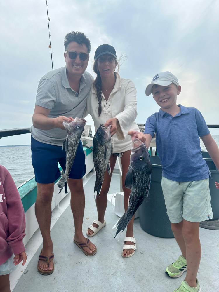 a group of people standing next to a person holding a fish