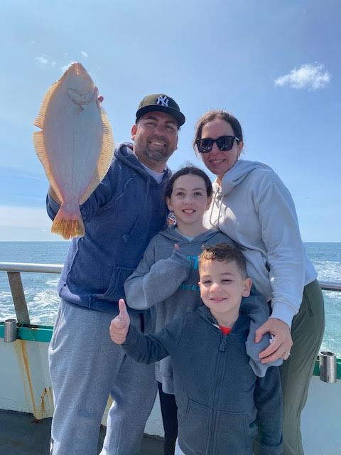 a group of people posing for a fish in the water