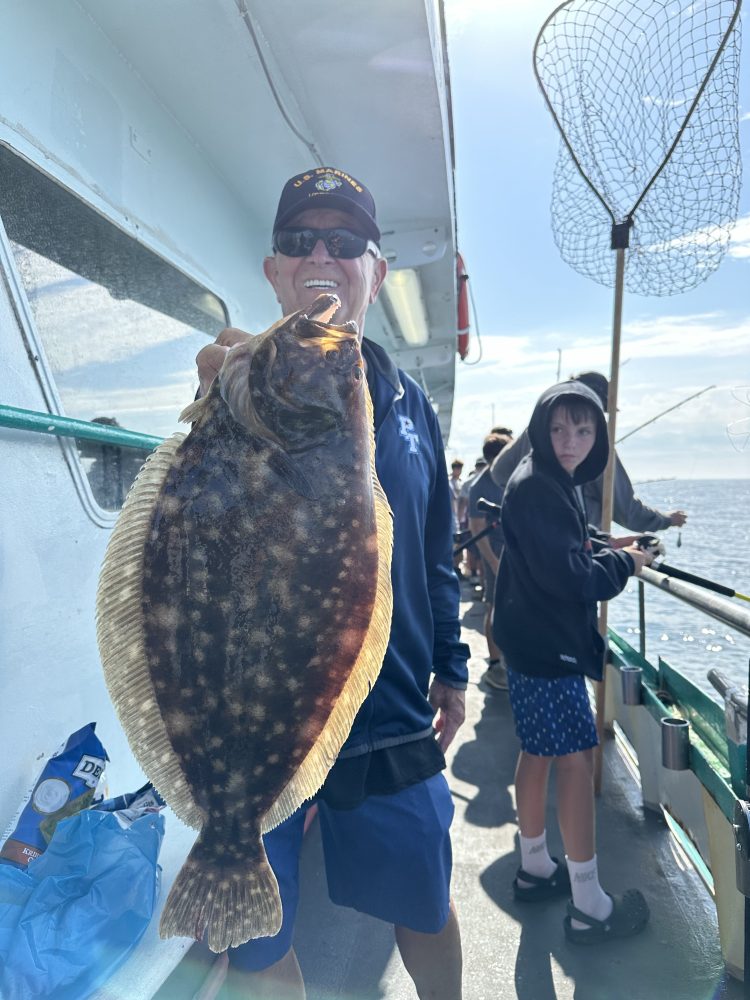 a person holding a fish on a boat posing for the camera