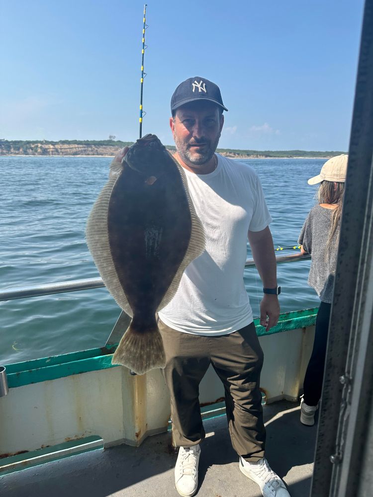 a man holding a fish on a boat in a body of water