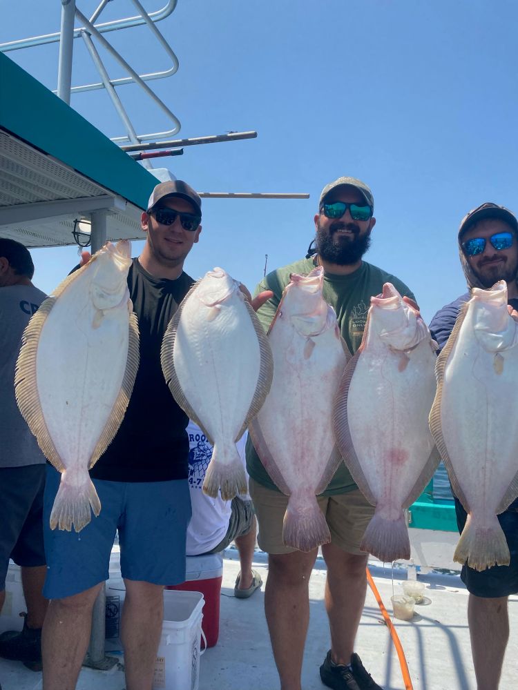 a group of people standing next to a man holding a fish