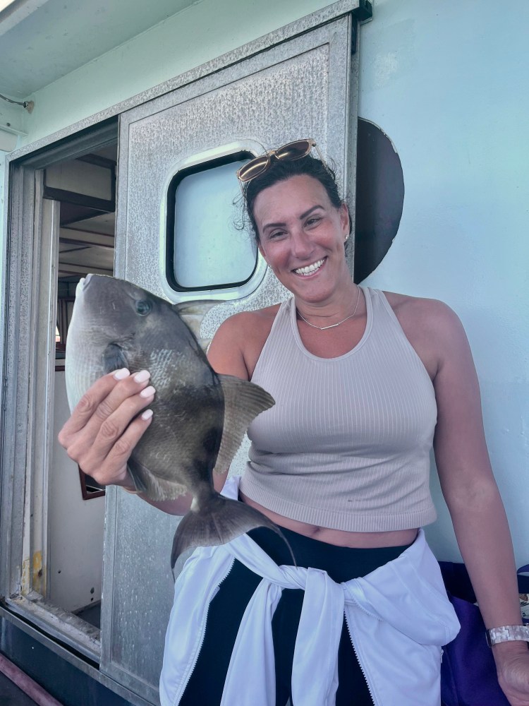 a person holding a fish posing for the camera