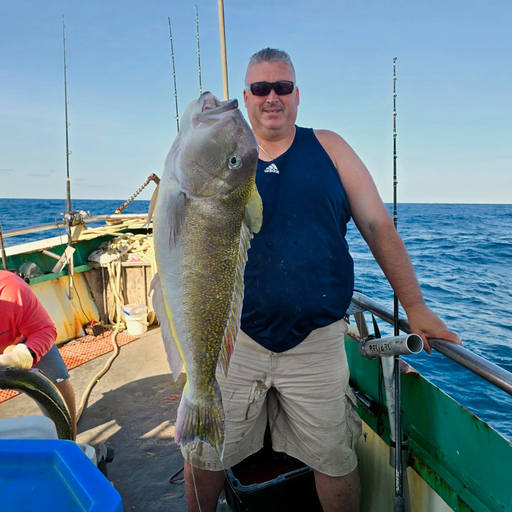 a man holding a fish on a boat