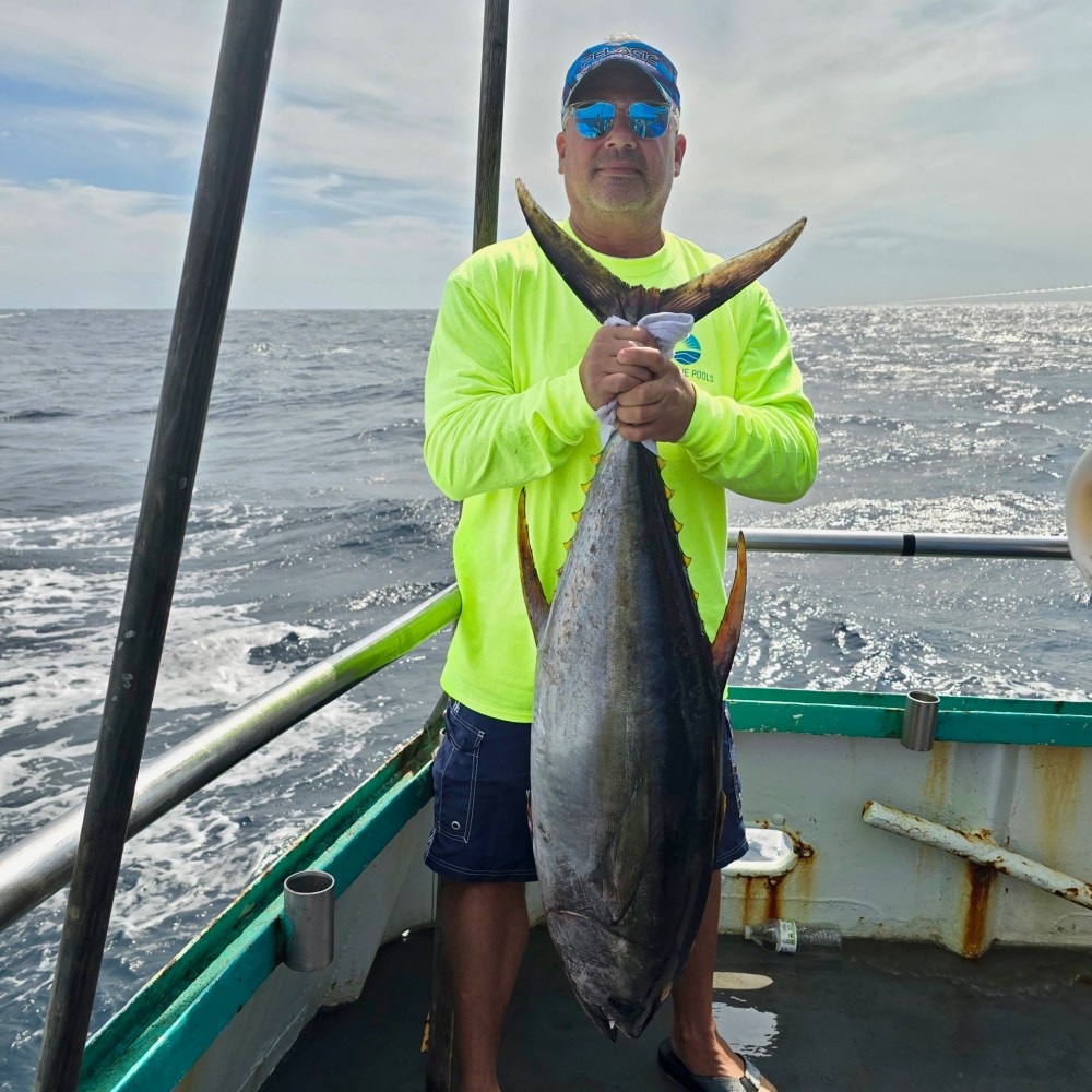 a man holding a fish on a boat in a body of water