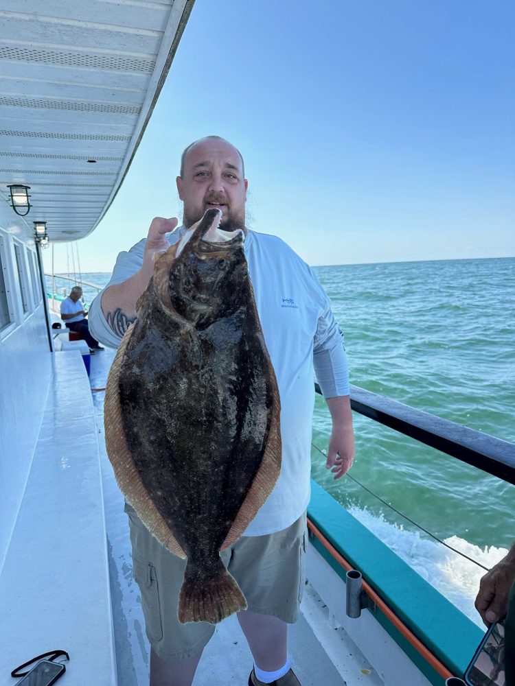 a man holding a fish on a boat in the water