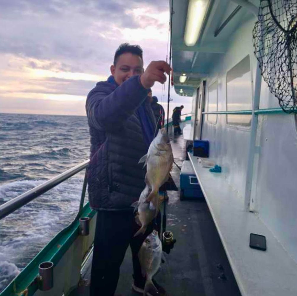 a man holding a fish on a boat