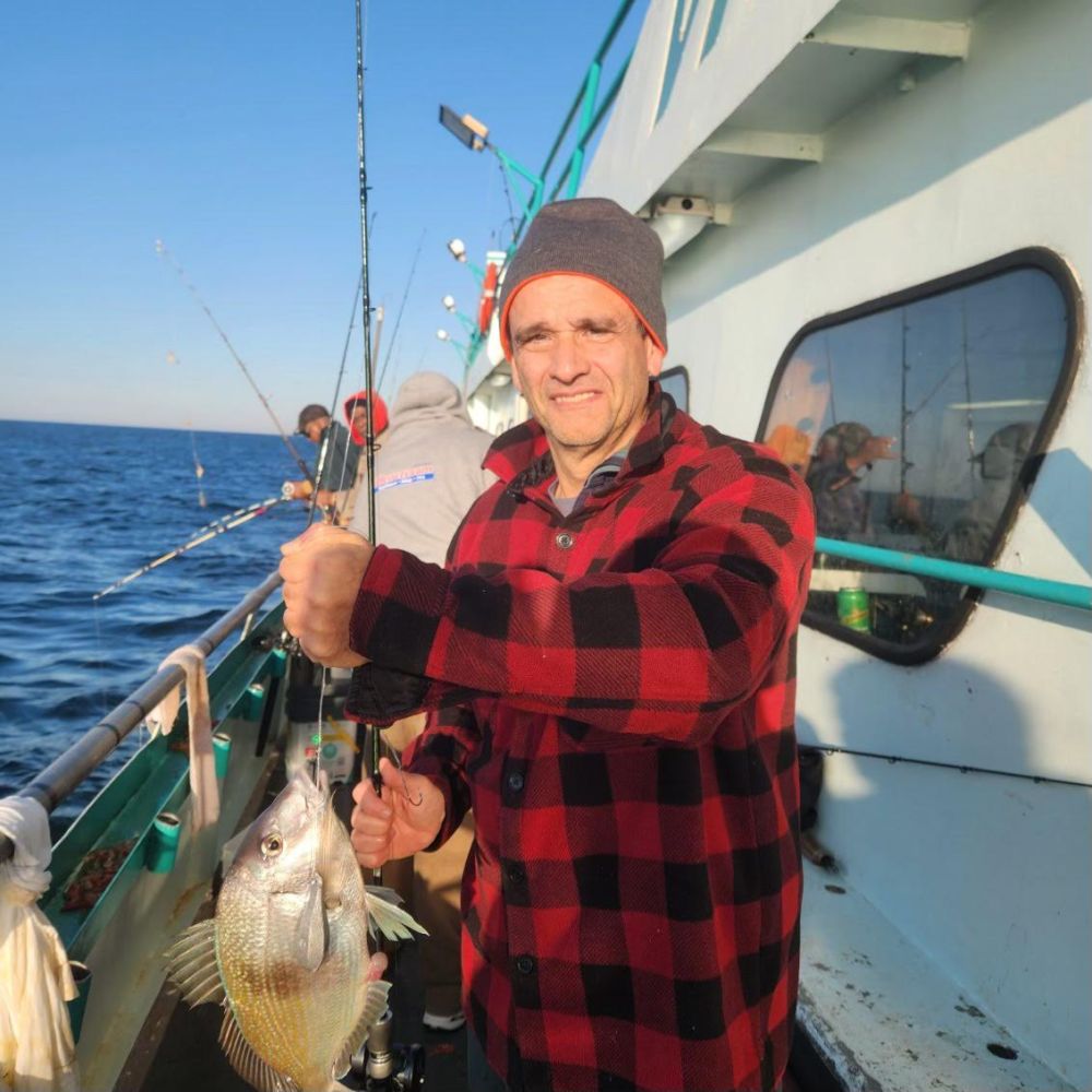 a man holding a fish on a boat