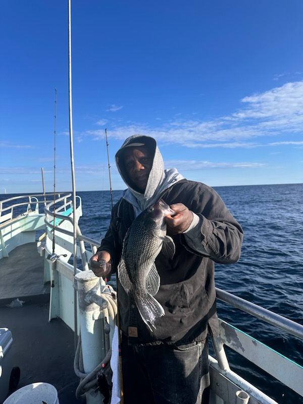 a man holding a fish on a boat in the water